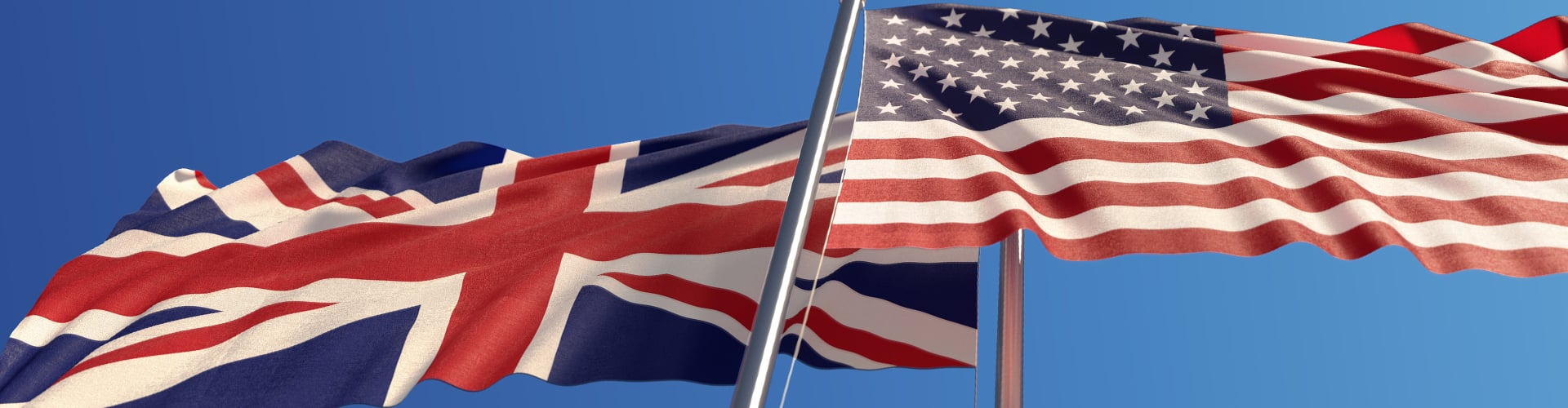 UK and US flags flying on a blue sky day