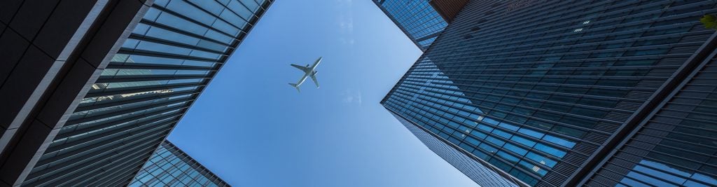 Airplane flying on blue sky over buildings