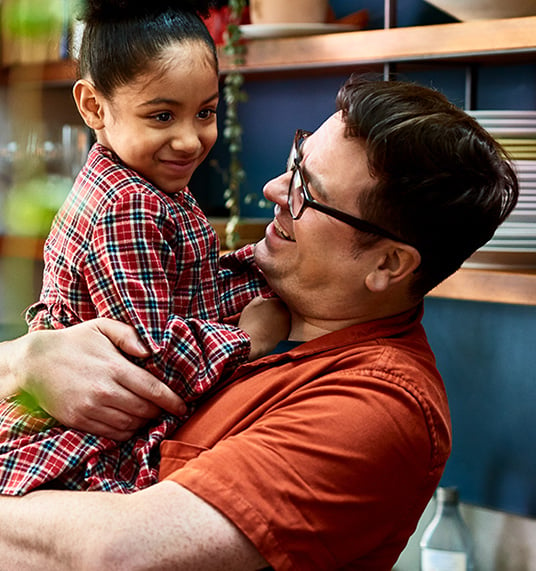 A smiling man holds a girl in his arms