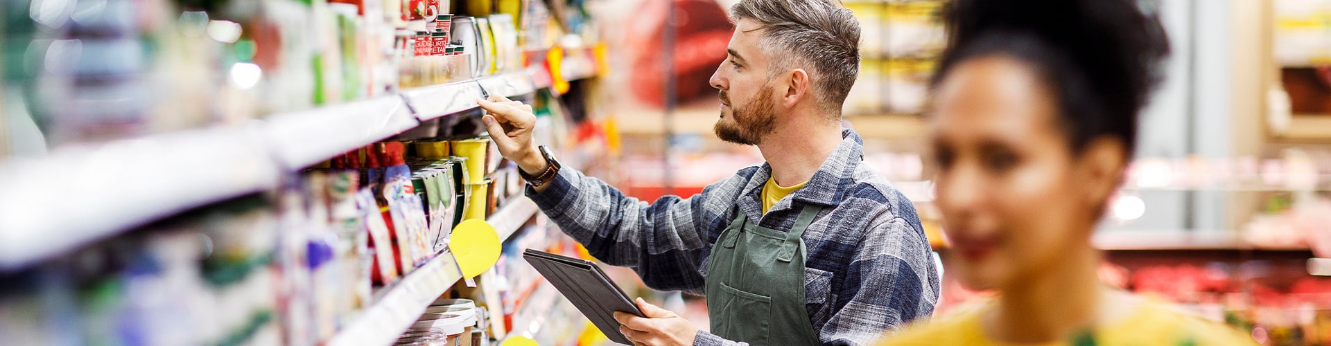 Customer and shop assistant at shelves in supermarket