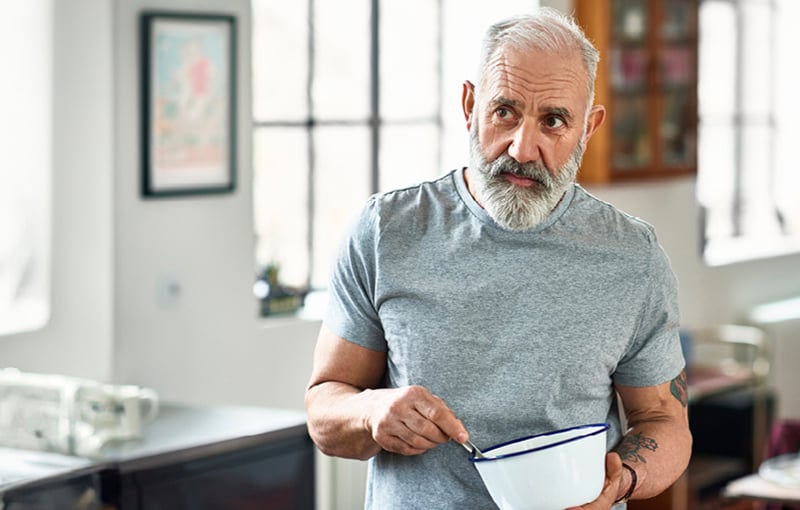 Man standing in kitchen holding bowl