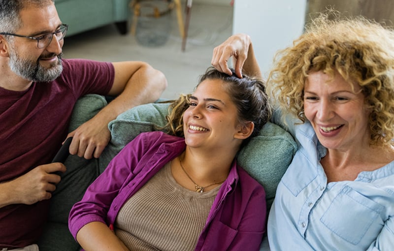 Man and two women sitting on sofa