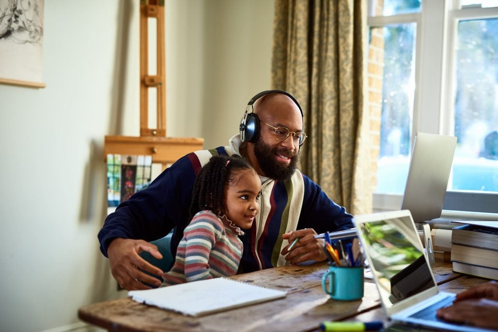 A man and a child sitting in front of a laptop