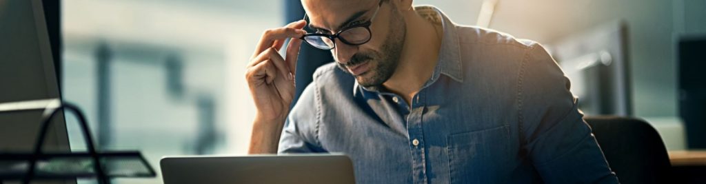 Man with glasses looking at laptop screen