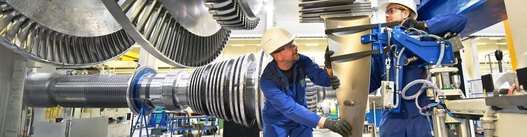 Two men with hard hats working on assembly line